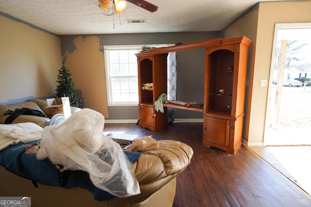 living room featuring ceiling fan, dark hardwood / wood-style flooring, and a textured ceiling