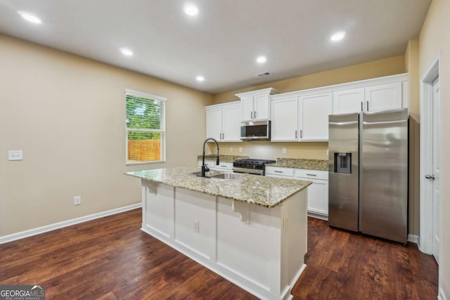 kitchen featuring sink, white cabinetry, a center island with sink, stainless steel appliances, and light stone countertops