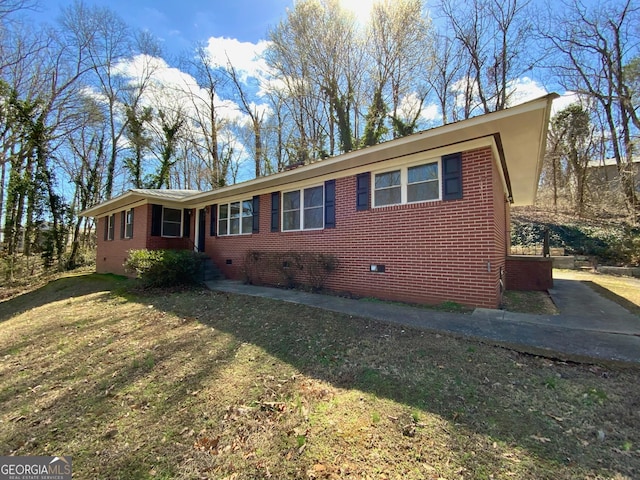 view of home's exterior with brick siding, crawl space, and a lawn