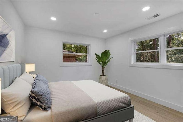 bedroom with multiple windows and light hardwood / wood-style flooring