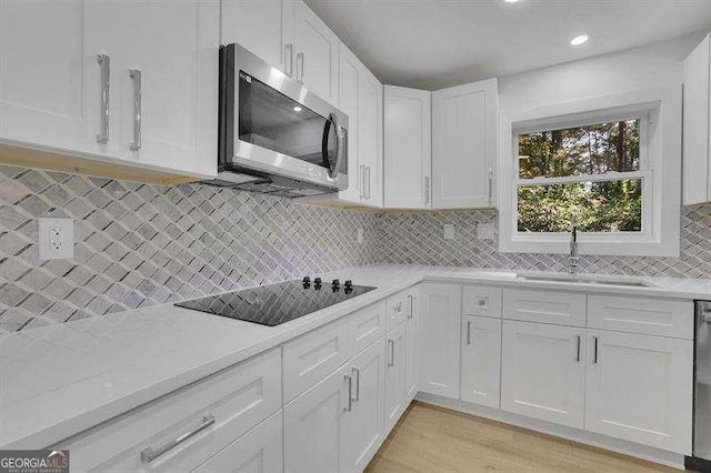 kitchen featuring light stone countertops, white cabinets, appliances with stainless steel finishes, sink, and backsplash