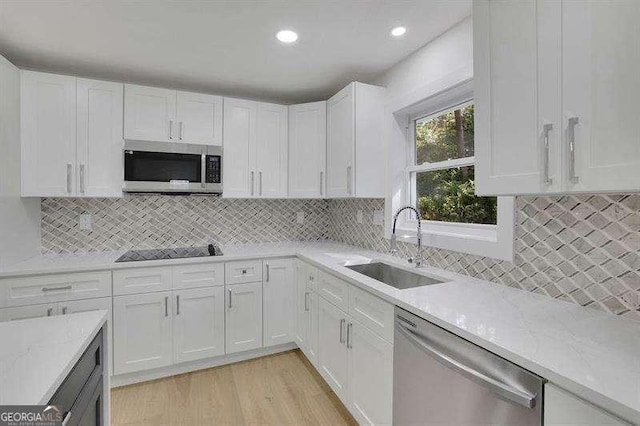 kitchen with light stone countertops, white cabinets, appliances with stainless steel finishes, and sink