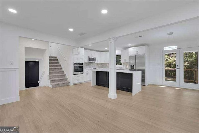 kitchen with backsplash, a center island, pendant lighting, stainless steel appliances, and white cabinets