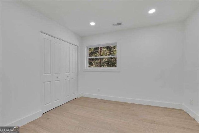 unfurnished bedroom with light wood-type flooring and a closet