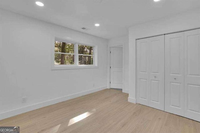 unfurnished bedroom with light wood-type flooring and a closet