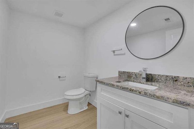 bathroom featuring toilet, vanity, and hardwood / wood-style flooring