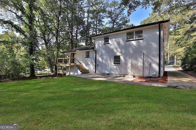 rear view of property with a wooden deck and a lawn