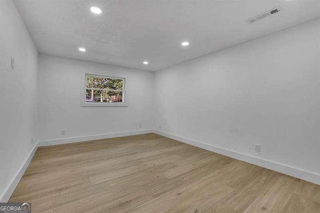 spare room featuring light wood-type flooring and a textured ceiling