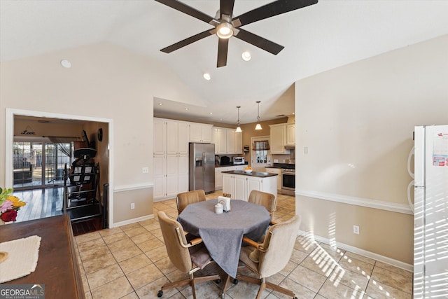 dining space featuring ceiling fan, light tile patterned floors, and vaulted ceiling