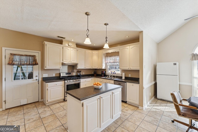 kitchen with a textured ceiling, light tile patterned floors, stainless steel appliances, and pendant lighting