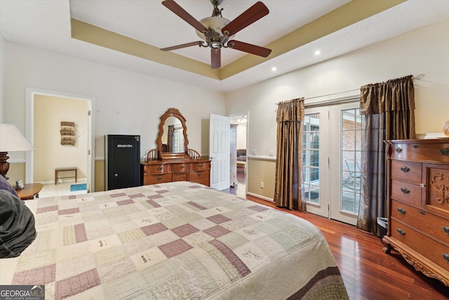 bedroom featuring hardwood / wood-style flooring, ceiling fan, a raised ceiling, and access to outside