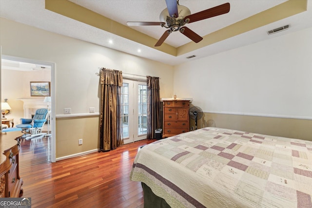 bedroom with a raised ceiling, ceiling fan, access to outside, and hardwood / wood-style flooring