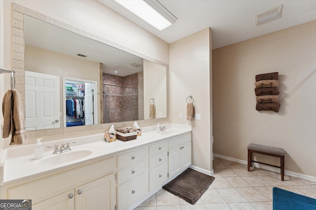 bathroom featuring a textured ceiling, tile patterned floors, vanity, and tiled shower