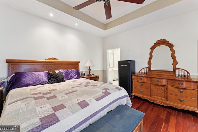 bedroom with ceiling fan, dark hardwood / wood-style floors, connected bathroom, and a raised ceiling