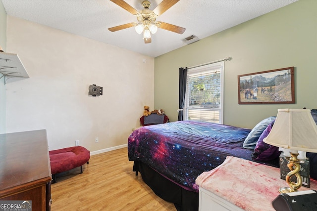 bedroom with light wood-type flooring, ceiling fan, and a textured ceiling