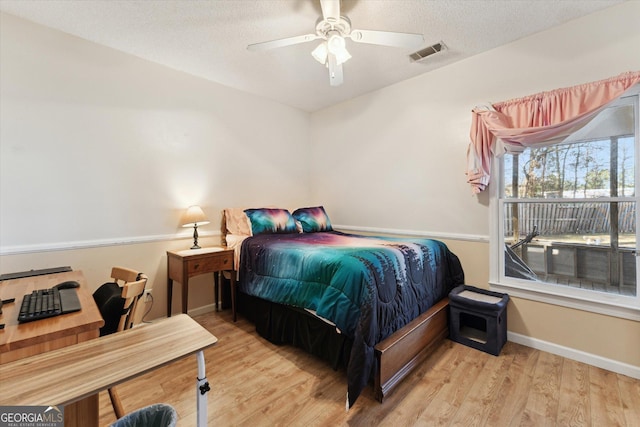 bedroom with ceiling fan, a textured ceiling, and light hardwood / wood-style flooring