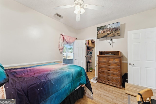 bedroom with a textured ceiling, ceiling fan, a closet, and light hardwood / wood-style floors