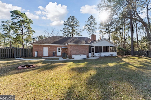 single story home featuring a sunroom, a fire pit, and a front yard