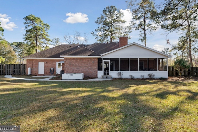 back of house featuring a lawn and a sunroom