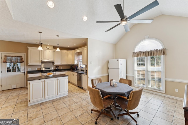 kitchen with decorative light fixtures, lofted ceiling, a textured ceiling, stainless steel appliances, and light tile patterned floors