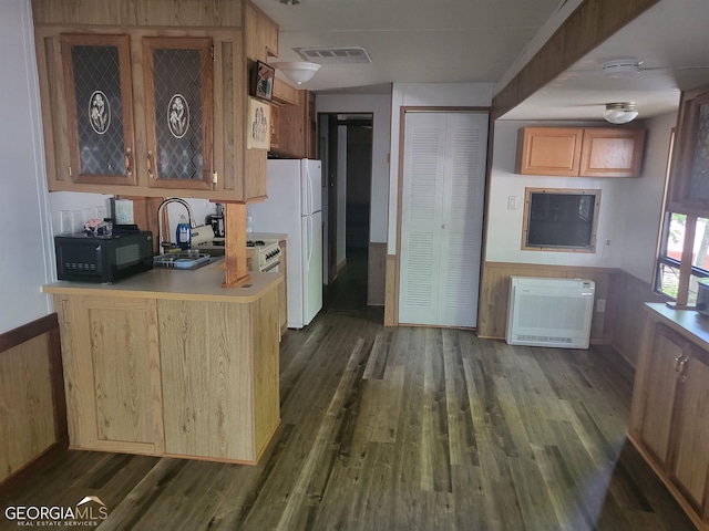 kitchen with heating unit, kitchen peninsula, dark hardwood / wood-style flooring, and wooden walls