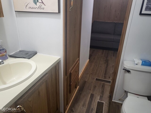 bathroom with toilet, wood-type flooring, and vanity