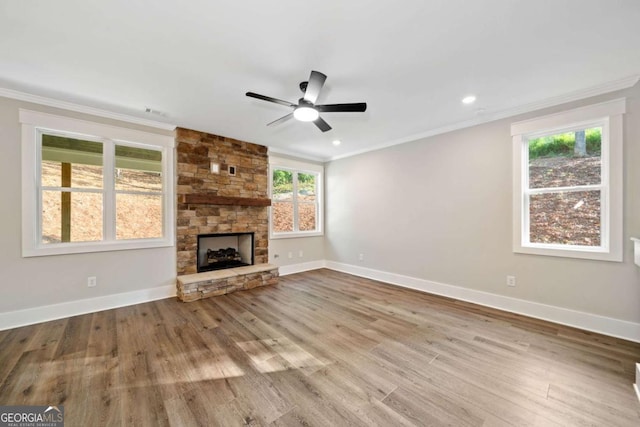 unfurnished living room with ceiling fan, a wealth of natural light, crown molding, and a fireplace