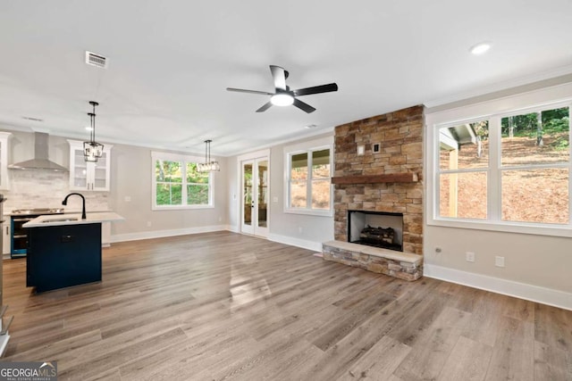 unfurnished living room featuring sink, ceiling fan with notable chandelier, ornamental molding, and hardwood / wood-style flooring