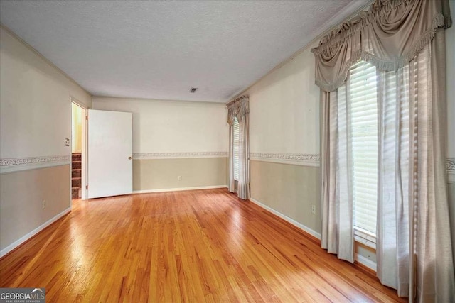 spare room featuring light wood-type flooring and a textured ceiling