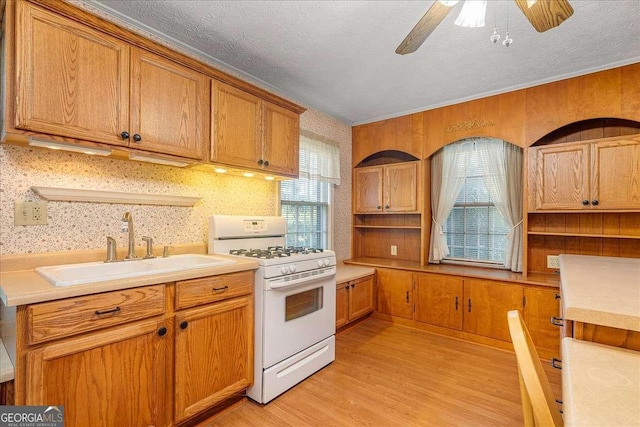 kitchen with a textured ceiling, sink, ceiling fan, white range with gas stovetop, and light hardwood / wood-style flooring