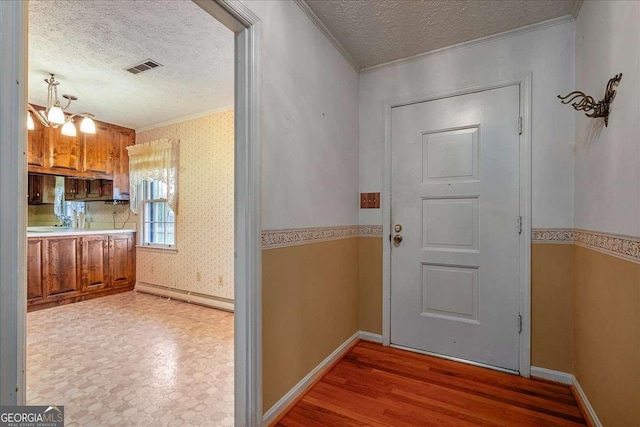 doorway to outside featuring a notable chandelier, crown molding, a textured ceiling, and hardwood / wood-style flooring