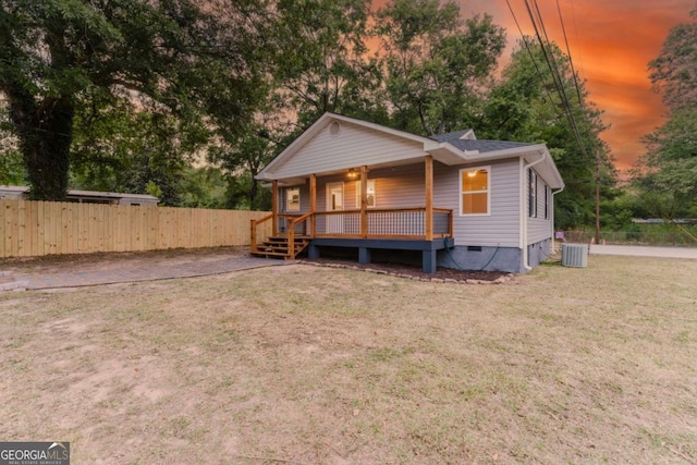 back house at dusk featuring a lawn and central air condition unit