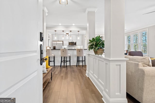 corridor with dark hardwood / wood-style flooring, crown molding, and decorative columns