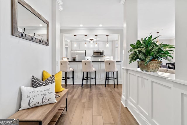 hallway with light wood-type flooring and crown molding