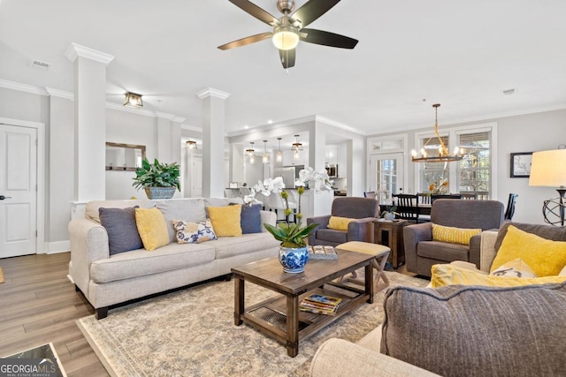 living room featuring decorative columns, ceiling fan with notable chandelier, ornamental molding, and light wood-type flooring