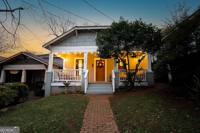 bungalow-style home with covered porch and a lawn