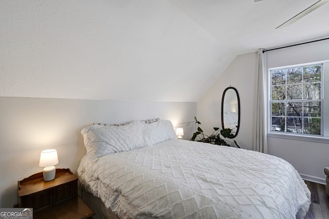 bedroom with dark wood-type flooring and lofted ceiling