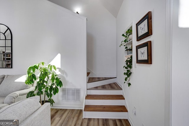 stairs featuring vaulted ceiling and hardwood / wood-style floors