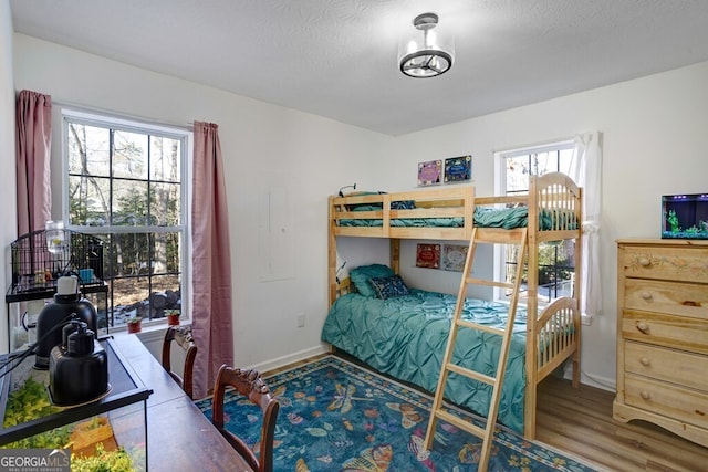 bedroom featuring hardwood / wood-style flooring, multiple windows, and a textured ceiling