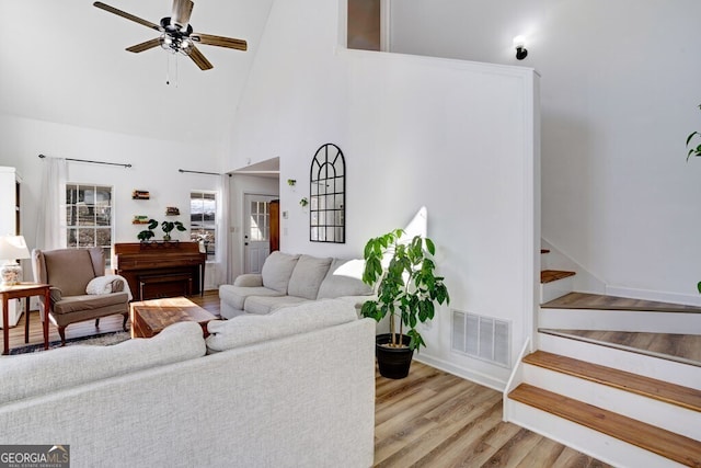 living room with high vaulted ceiling, ceiling fan, and light hardwood / wood-style flooring