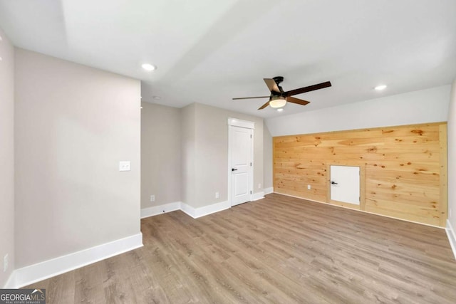 spare room with ceiling fan, wooden walls, and light hardwood / wood-style floors