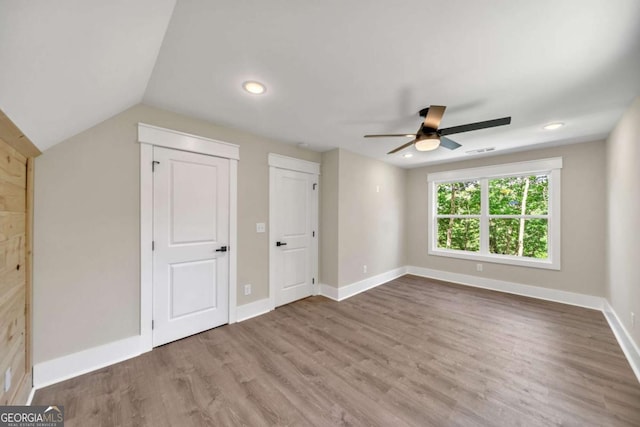 unfurnished bedroom with ceiling fan, hardwood / wood-style floors, and lofted ceiling