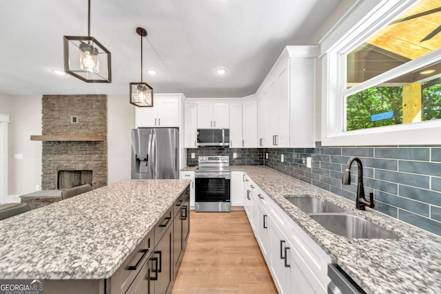 kitchen with a center island, sink, stainless steel appliances, and white cabinetry