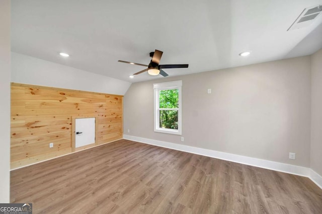 interior space with wood-type flooring, vaulted ceiling, and wooden walls