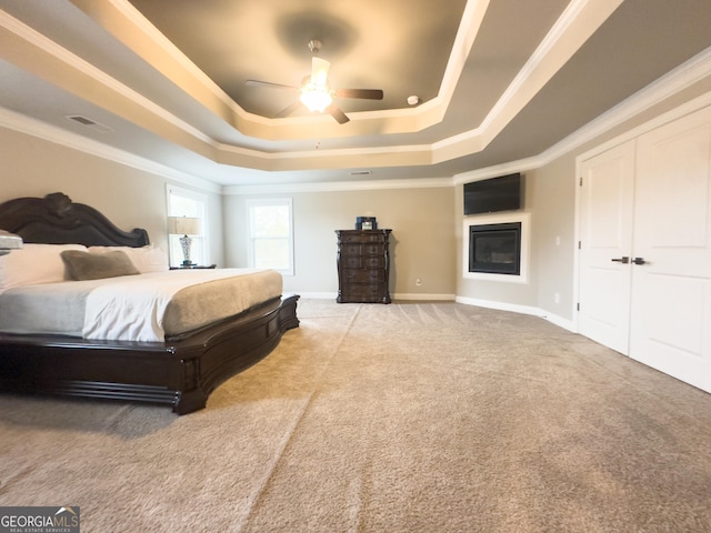 bedroom featuring ceiling fan, crown molding, a raised ceiling, and carpet floors