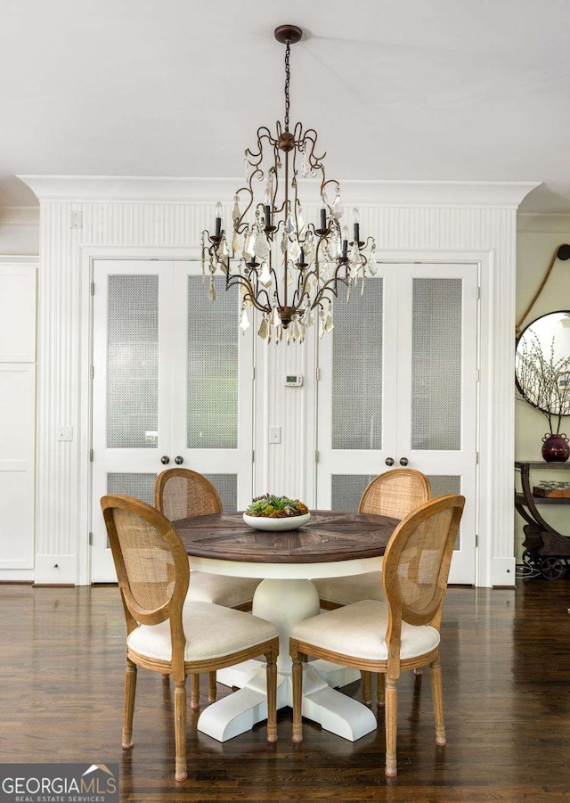 dining room with french doors, dark hardwood / wood-style floors, an inviting chandelier, and ornamental molding