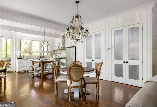 dining area with dark wood-type flooring, a chandelier, crown molding, and french doors