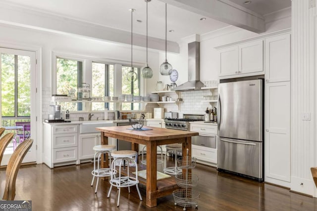 kitchen with pendant lighting, white cabinets, wall chimney exhaust hood, backsplash, and stainless steel refrigerator