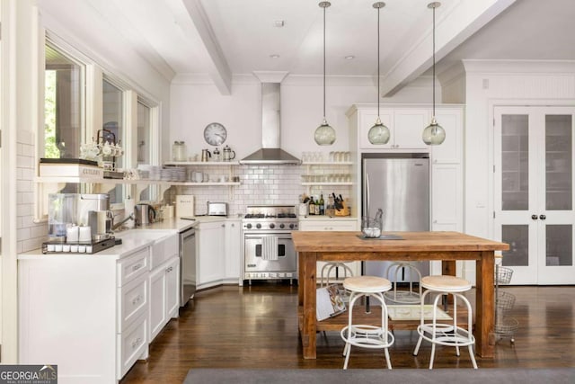 kitchen with backsplash, pendant lighting, white cabinetry, appliances with stainless steel finishes, and wall chimney exhaust hood