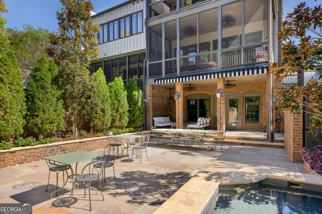 rear view of property with a balcony, a sunroom, and a patio